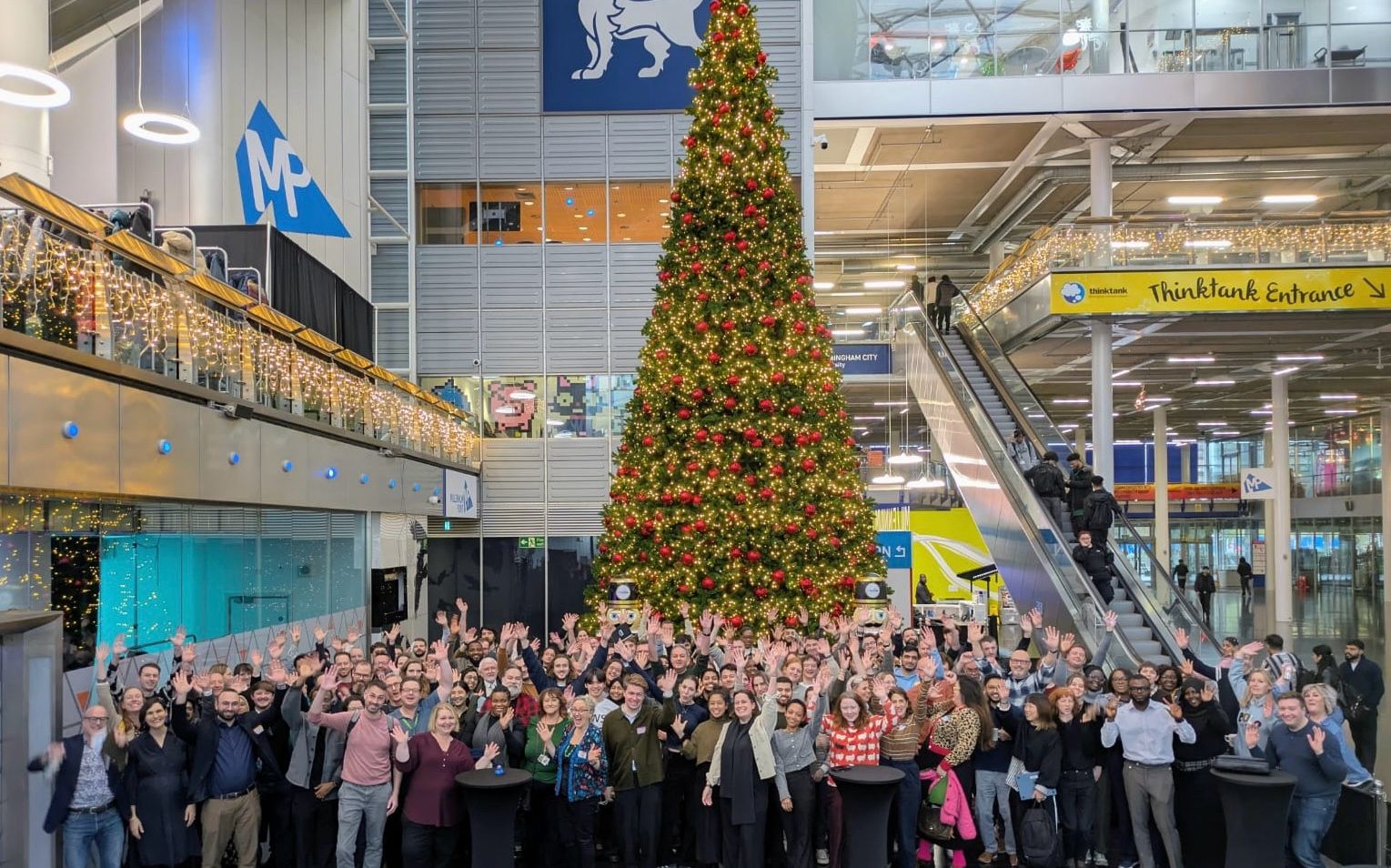 A large group of people assembled in front of a Christmas tree